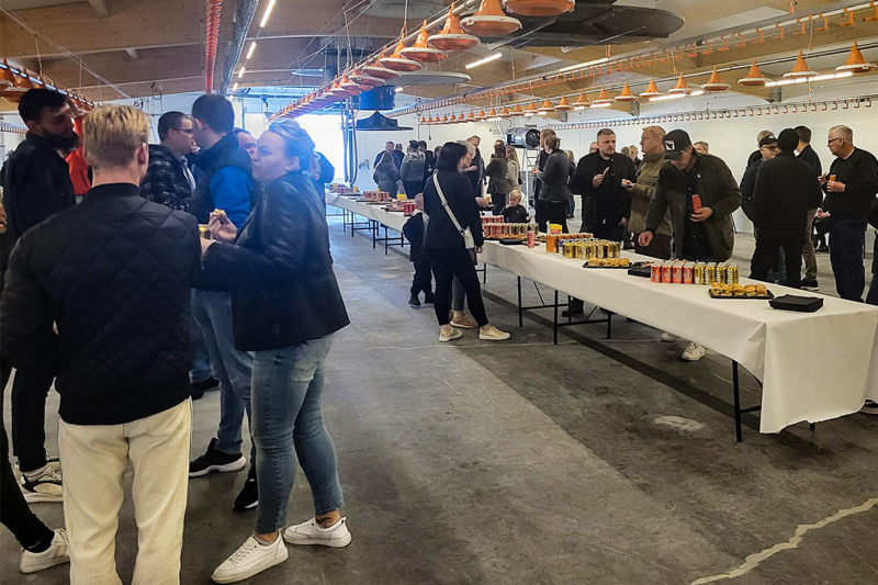 В новом птичнике для содержания бройлеров гости обсуждают технологии и разведение животных; им предлагаются напитки и закуски.