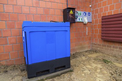 Rechteckiger blauer Behälter für Betriebsmittel an Stallwand 